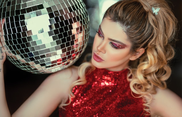 Woman in red sequins with disco ball for retro skate night
