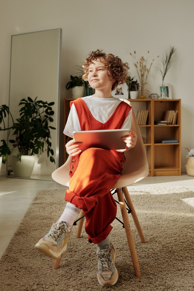 Kid in chair holding tablet
