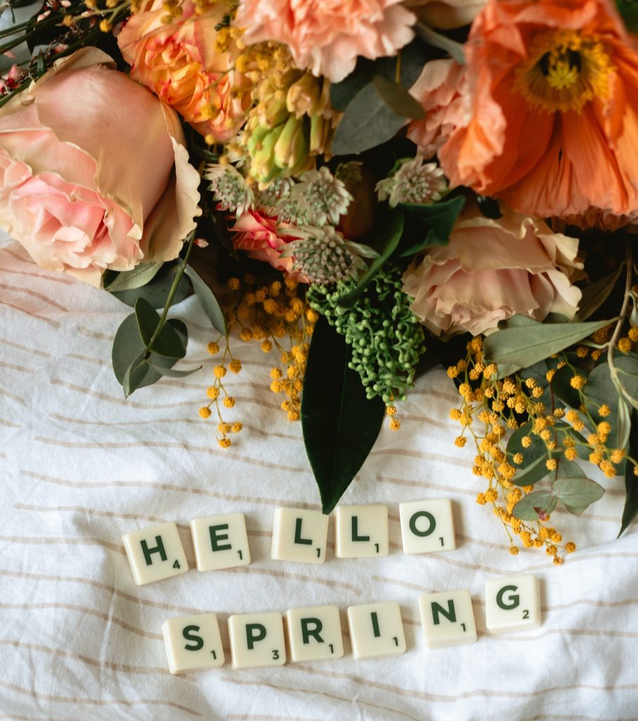 Flowers with letter tiles spelling “hello spring”
